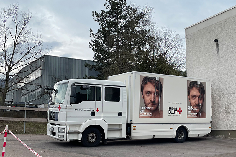 A white truck stands in front of a production hall.